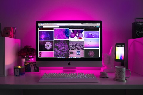 Desktop with images on the screen, backlit with neon pink light.