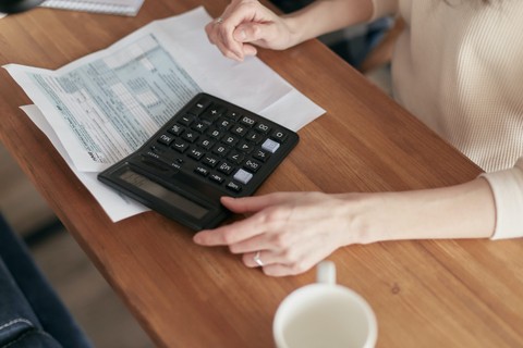 Person calculating bills with a calculator.