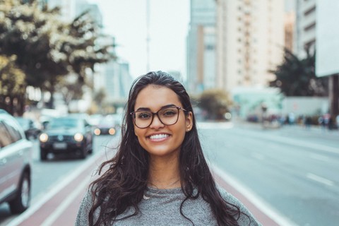 Latina woman smiling with a cityscape behind her.
