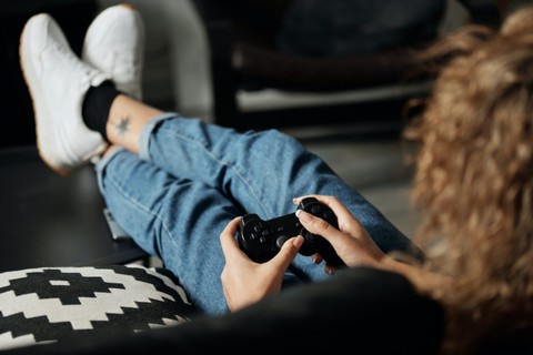 Person with feet up on a table and holding a video game controller.